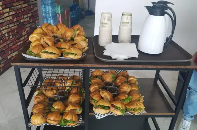 Carrito con sándwiches, termos de café y vasos para servicio para llevar