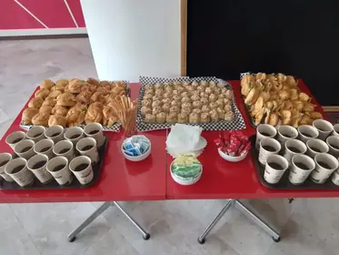 Coffee break con pan, postres y bebidas sobre mesa roja